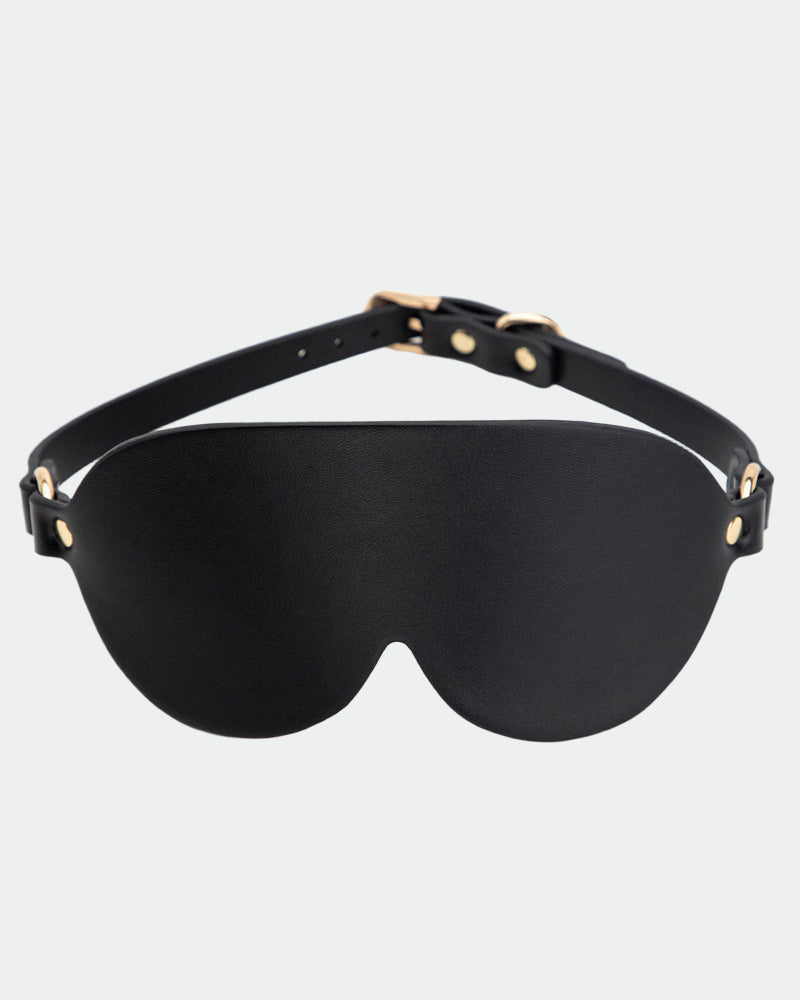 Black leather sunshade eye mask with adjustable strap and gold hardware for intimate sessions.