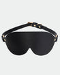 Black leather sunshade eye mask with adjustable strap and gold hardware for intimate sessions.