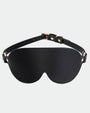 Black leather sunshade eye mask with adjustable strap and gold hardware for intimate sessions.