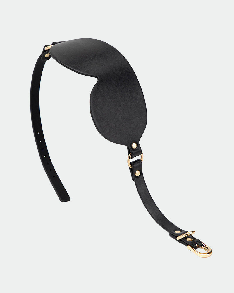 Black leather eye mask with gold hardware and adjustable strap for sensual exploration.