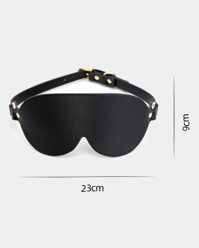 Black leather eye mask with adjustable strap and gold hardware for sensual exploration.