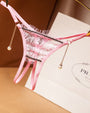 Pink crotchless thong with floral lace, pearl pendant, and low waist. Sexy lingerie.