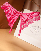 Pink lace crotchless thong with floral design, low waist, and Prada shopping bag background
